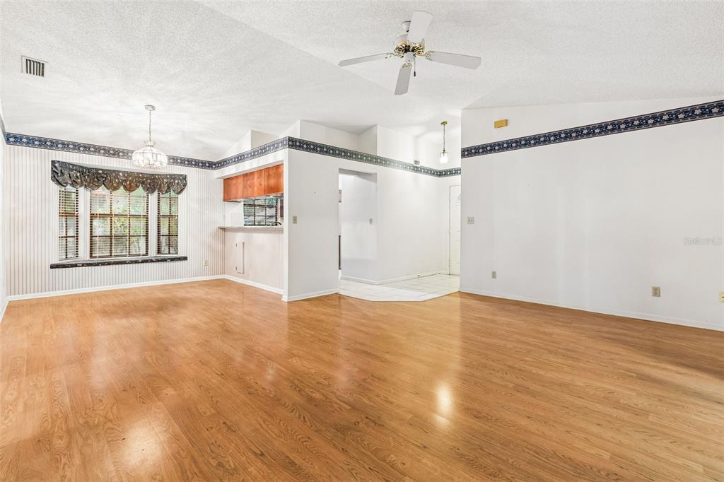 A spacious living room with light wood flooring, a ceiling fan, and blue wallpaper border — 11301 MAYBROOK AVENUE, RIVERVIEW, FL