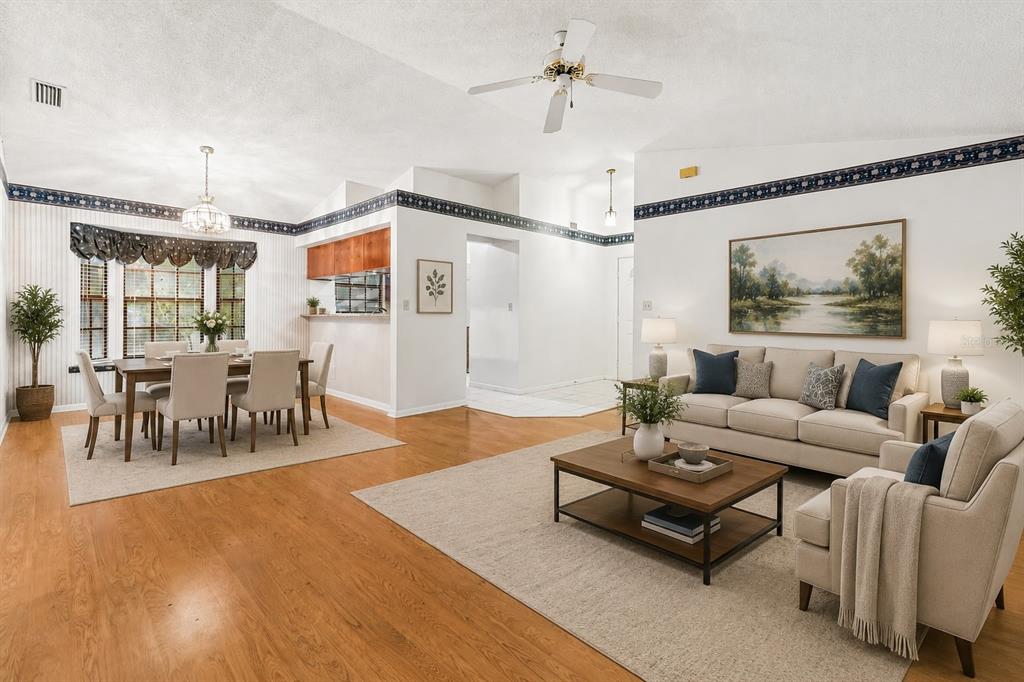 A living and dining room with hardwood floors, a ceiling fan, and blue wallpaper borders — 11301 MAYBROOK AVENUE, RIVERVIEW, FL