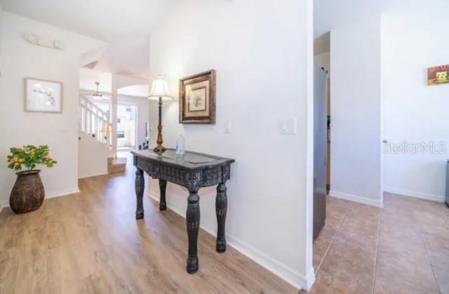 A foyer features light wood-look flooring, a dark ornate console table, and a lamp — 1179 S BEACH CIRCLE, KISSIMMEE, FL