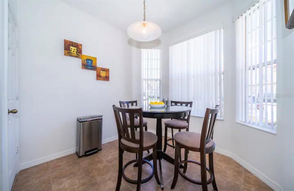A dining nook features a round table with four chairs, tile flooring, and vertical blinds — 1179 S BEACH CIRCLE, KISSIMMEE, FL