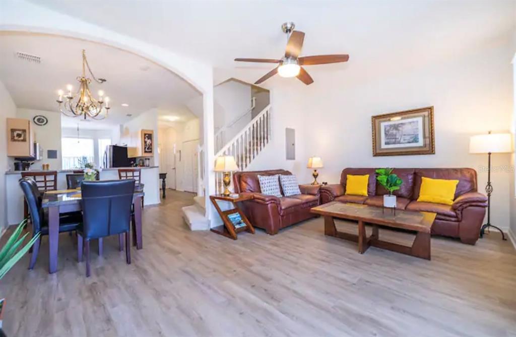 An open-concept living and dining area features wood-look flooring, a ceiling fan, and stairs — 1179 S BEACH CIRCLE, KISSIMMEE, FL