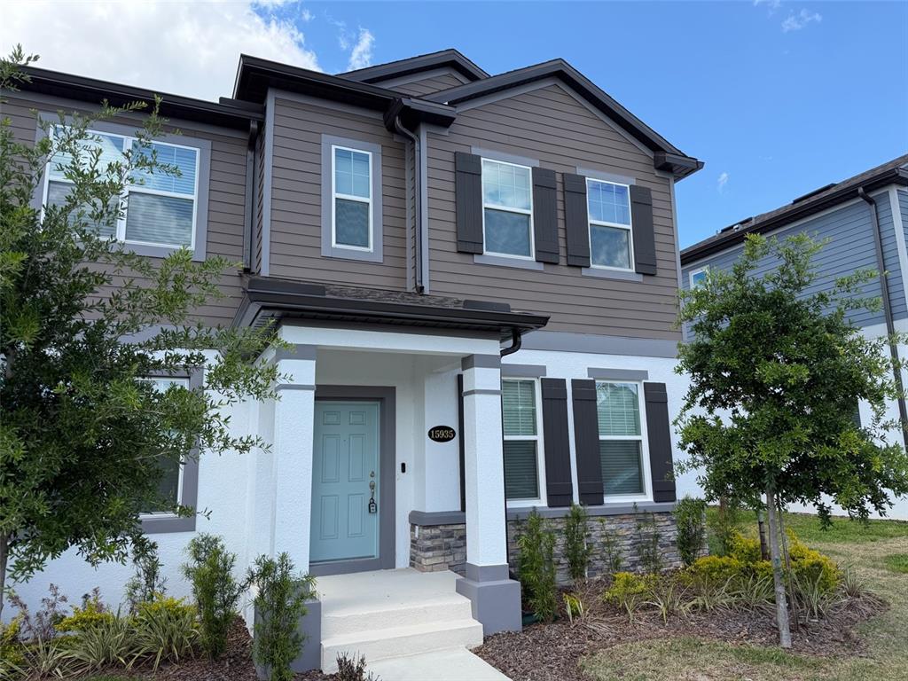 A two-story house exterior features dark horizontal siding, white stucco, and a light blue door — 15935 GRAFTON WAY, WINTER GARDEN, FL