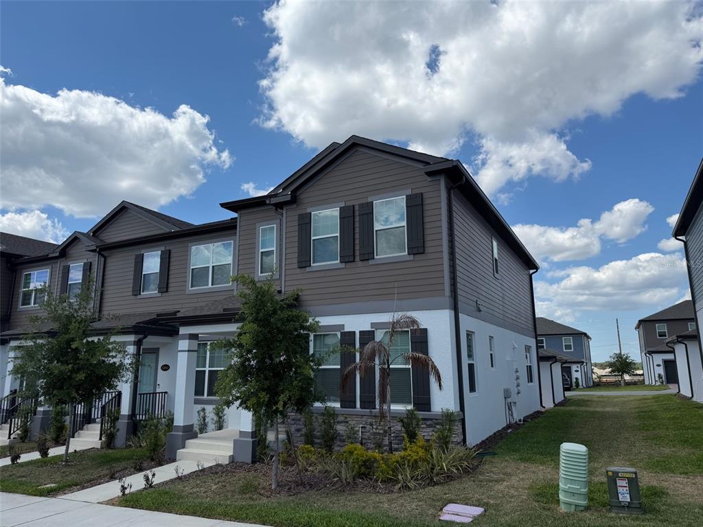 A two-story townhouse with brown horizontal siding, white stucco, and stone veneer exterior — 15935 GRAFTON WAY, WINTER GARDEN, FL