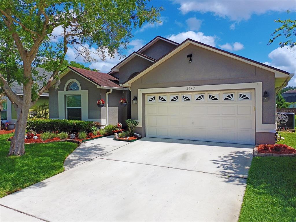 A single-story house with a two-car garage, a concrete driveway, and a landscaped front yard — 2679 ALAMOSA PLACE, LAKE MARY, FL