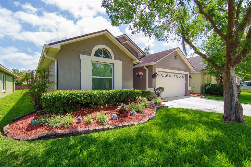 A single-story house with a tan exterior, a two-car garage, and a landscaped front yard — 2679 ALAMOSA PLACE, LAKE MARY, FL