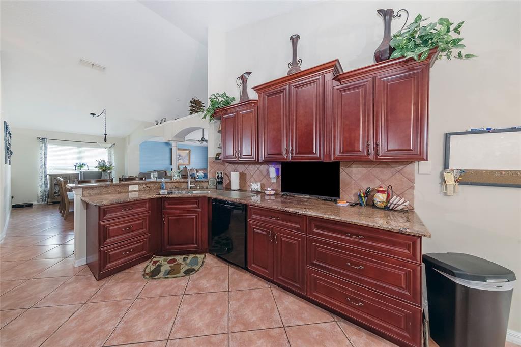 A kitchen features dark wood cabinets, granite countertops, and tile flooring — 2679 ALAMOSA PLACE, LAKE MARY, FL