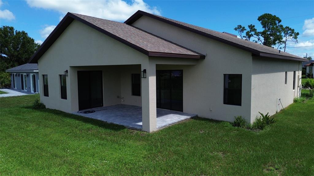 A beige house exterior features a covered patio with paved flooring and dark window frames — 273 ANTIS DRIVE, ROTONDA WEST, FL
