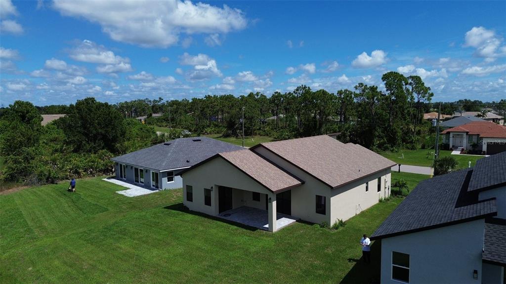 An aerial view shows three suburban houses with shingled roofs and green lawns under a sky — 273 ANTIS DRIVE, ROTONDA WEST, FL