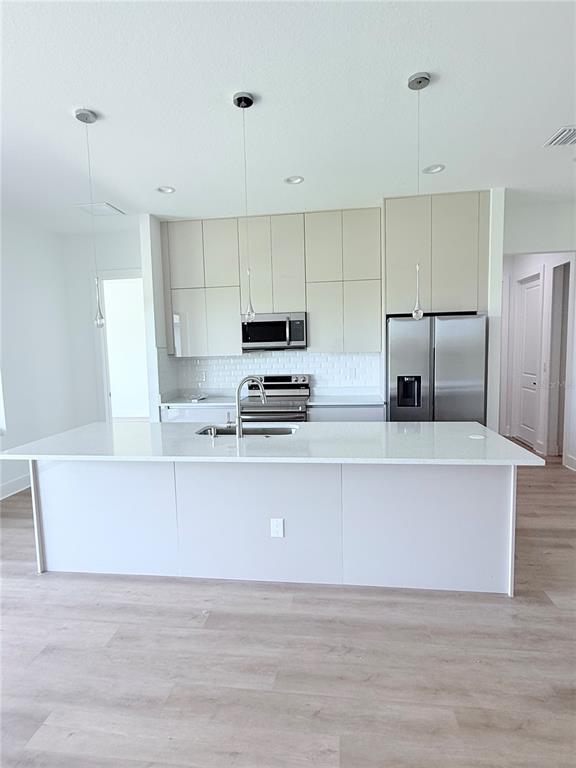 A modern kitchen features a large white island, stainless steel appliances, and light-colored cabinetry — 273 ANTIS DRIVE, ROTONDA WEST, FL