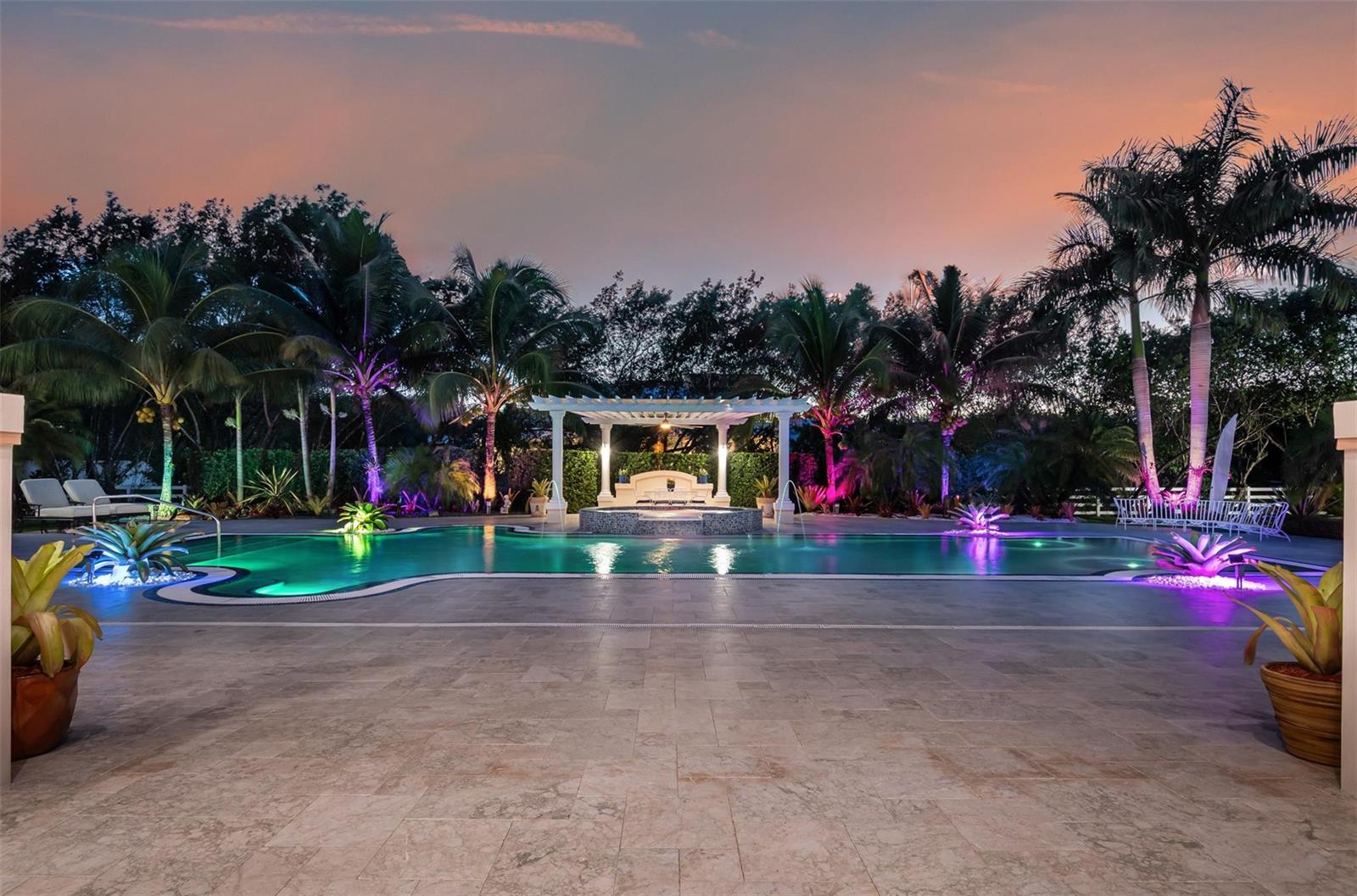 A swimming pool with a central gazebo and hot tub at dusk with landscape lighting — 5801 Estates Drive, Southwest Ranches FL 33330, SOUTHWEST RANCHES, FL