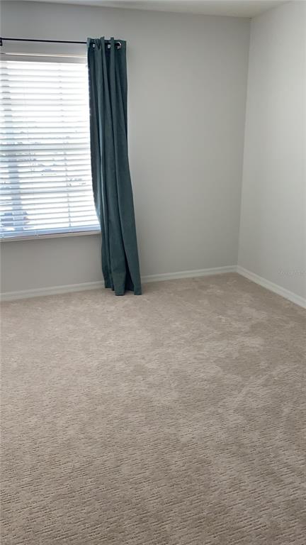 An empty bedroom features beige carpeting, light gray walls, and a window with teal curtains — 1949 SUMMER CLUB DRIVE UNIT 311, OVIEDO, FL
