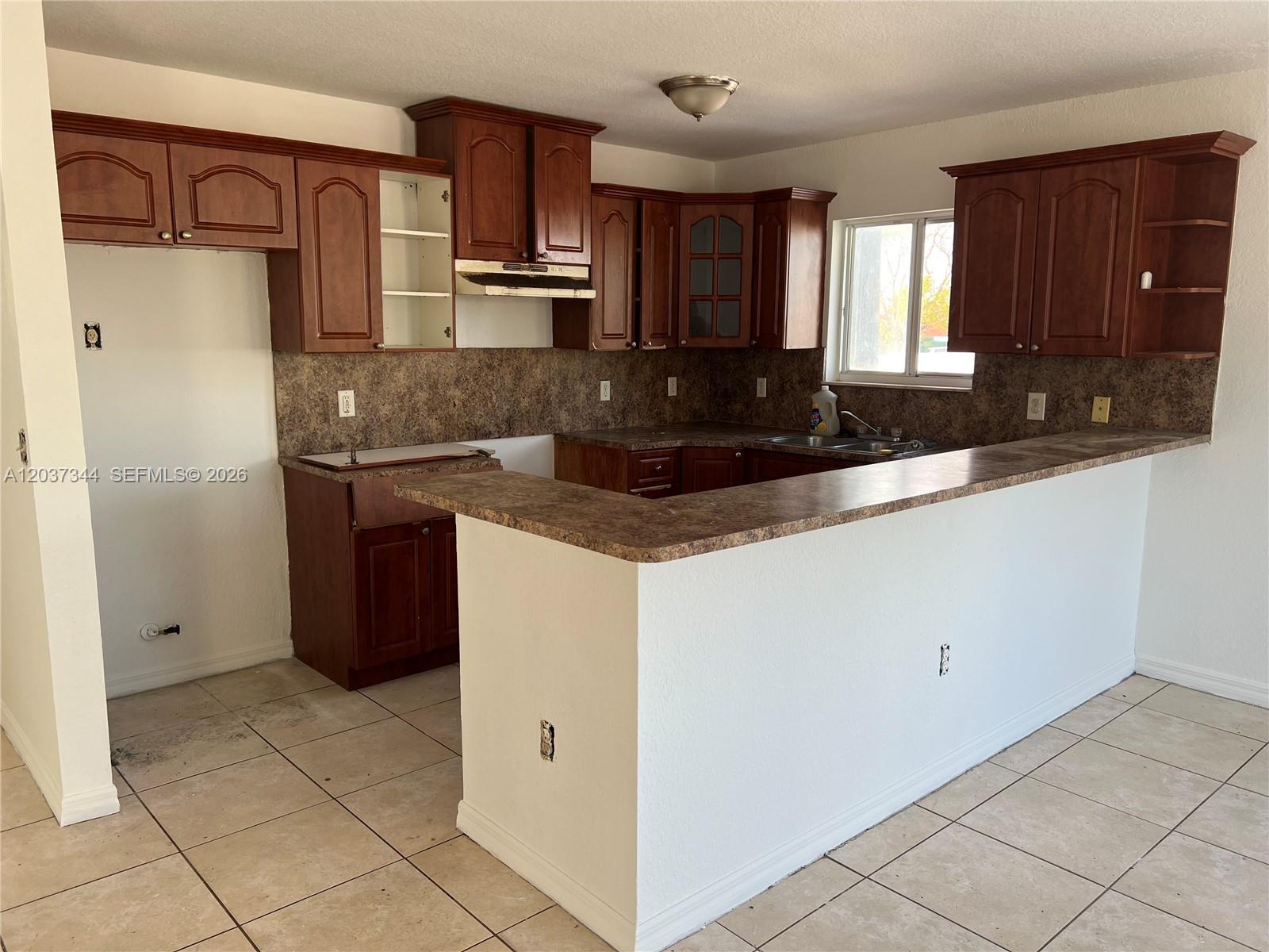 A kitchen features dark wood cabinets, brown laminate countertops, and light-colored floor tiles — 7012 NW 6th Ct # 7012, Miami FL 33150, MIAMI, FL