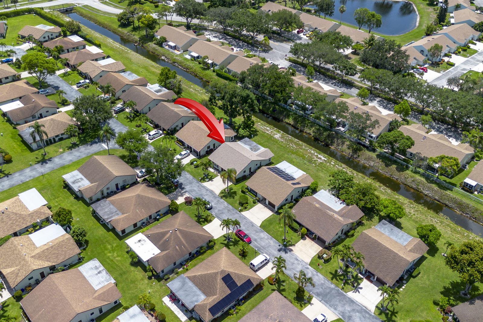 An aerial view shows a residential neighborhood with single-story homes, driveways, and a canal — 6320 Lakemont Circle, FL 33463, FL