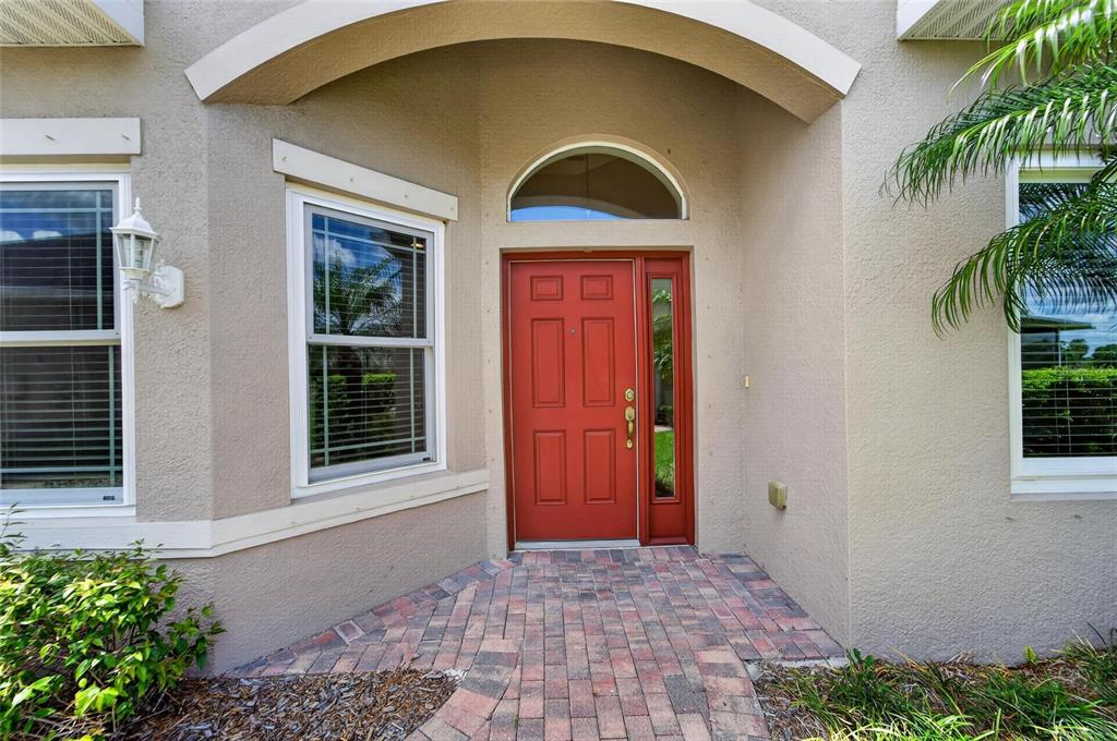 The exterior entrance features a red front door with a sidelight and arched transom window — 642 CHIPPER DRIVE, SUN CITY CENTER, FL