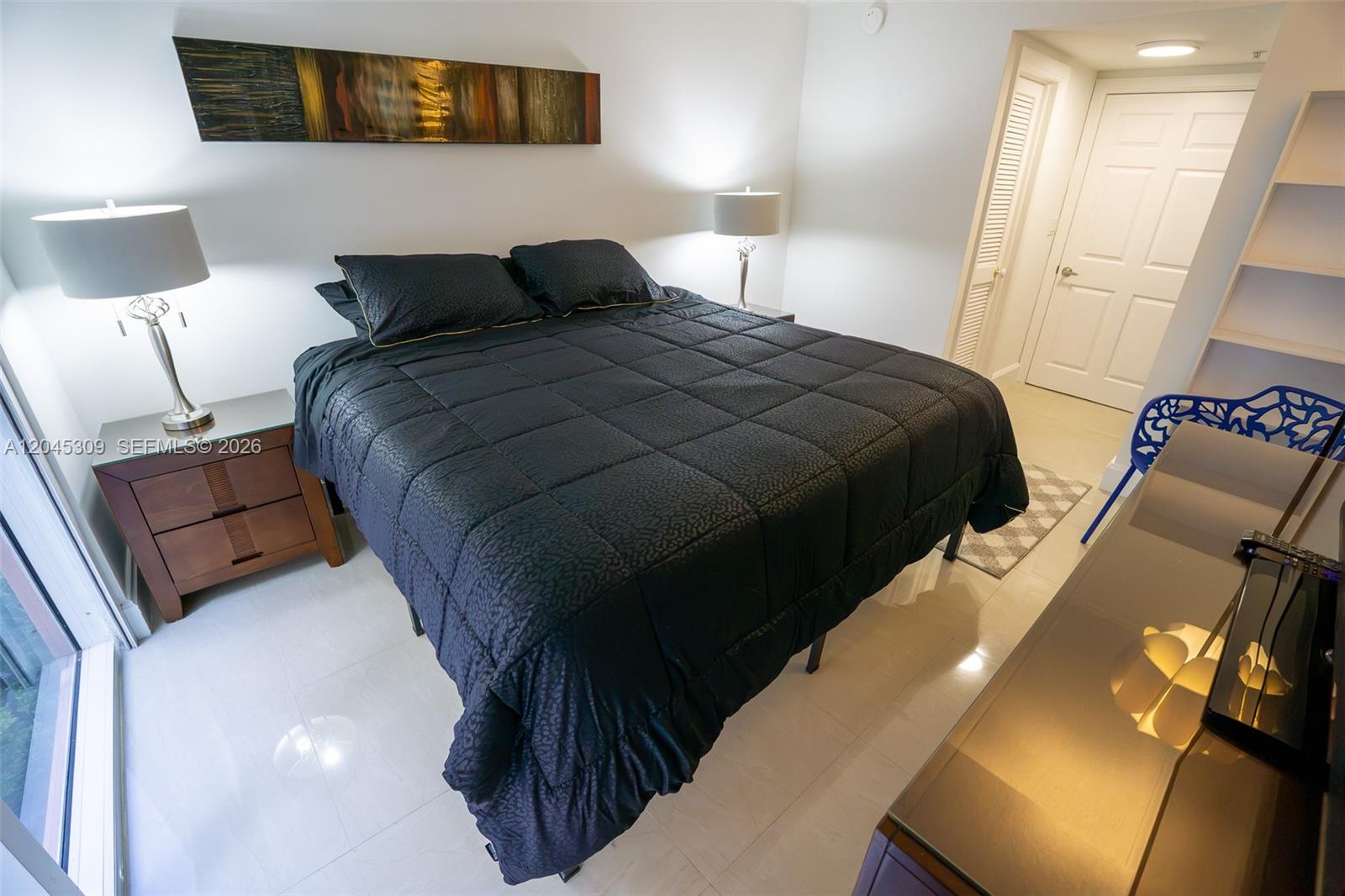 A bedroom features a black bed, two bedside lamps, and a piece of wall art — 2951 S Bayshore Dr # 716, Miami FL 33133, MIAMI, FL