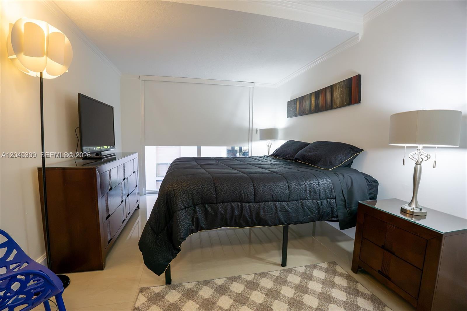 A bedroom features a black bed, a wooden dresser with a television, and two lamps — 2951 S Bayshore Dr # 716, Miami FL 33133, MIAMI, FL