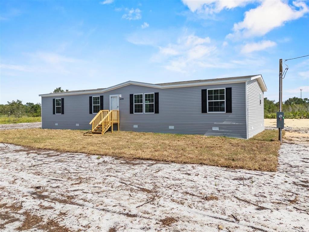 A single-story manufactured home with grey vinyl siding and a wooden front staircase — 2436 EDWIN STREET NE, WINTER HAVEN, FL