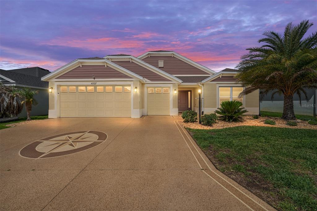 A single-story suburban house with a tan exterior, a two-car garage, and a paved driveway — 4537 BROOKE LANE, THE VILLAGES, FL