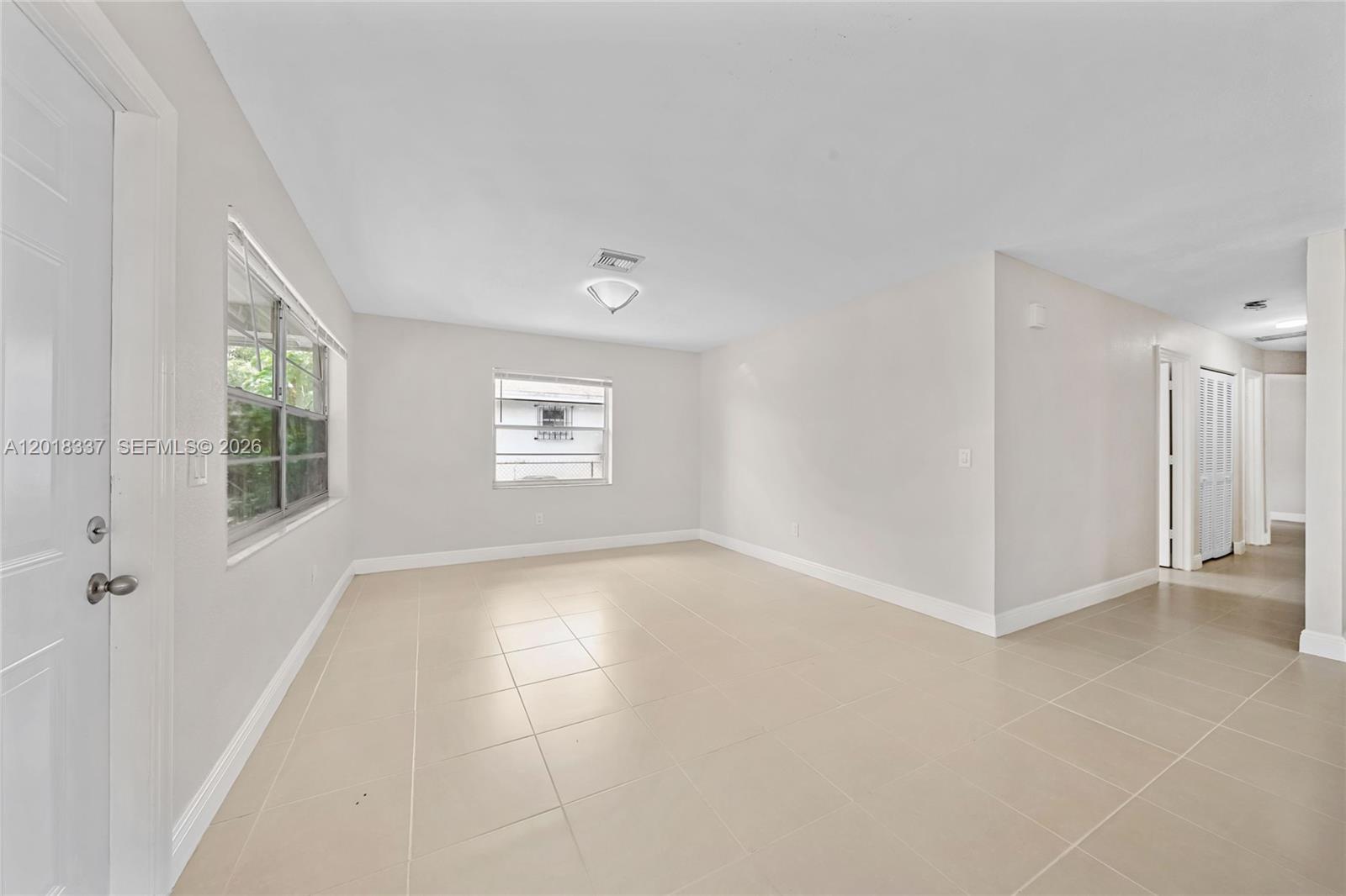 An empty room features light-colored tile flooring, white walls, and two windows — 429 Avenida Hermosa, West Palm Beach FL 33405, WEST PALM BEACH, FL