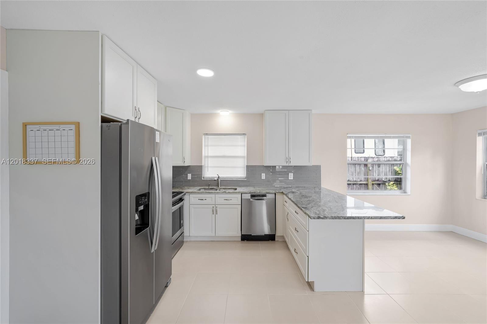 A kitchen features white cabinets, granite countertops, stainless steel appliances, and light-colored tile flooring — 429 Avenida Hermosa, West Palm Beach FL 33405, WEST PALM BEACH, FL