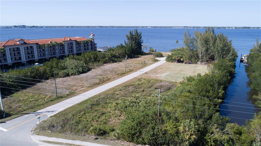 An aerial view shows a vacant lot with a paved path leading toward the water — 6162 LANDINGS WAY, PUNTA GORDA, FL