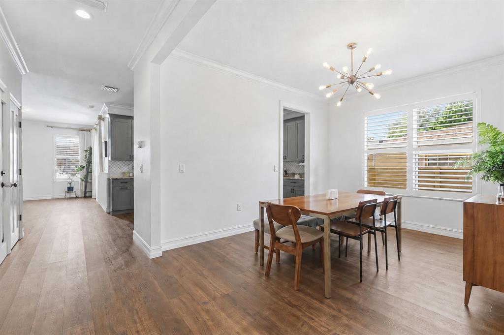 A dining room with a wooden table, chairs, a modern chandelier, and hardwood flooring — 2510 W CARMEN STREET, TAMPA, FL