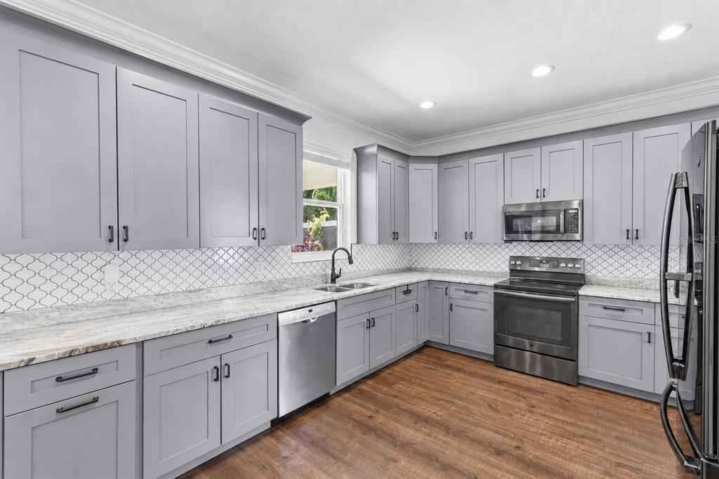 A kitchen features gray shaker cabinets, white marble-look countertops, and a patterned tile backsplash — 2510 W CARMEN STREET, TAMPA, FL
