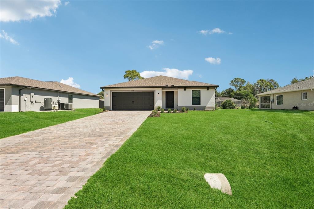 A single-story house with a paved driveway, a two-car garage, and a large front lawn — 3355 MONCRIEF AVENUE, NORTH PORT, FL