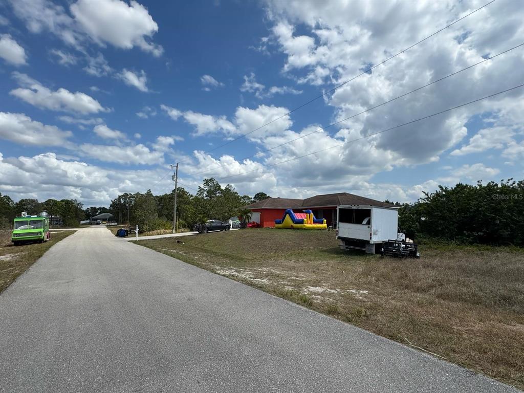 A red house with an inflatable bounce house sits on a lot near a road — 942 ARDMORE STREET, LEHIGH ACRES, FL