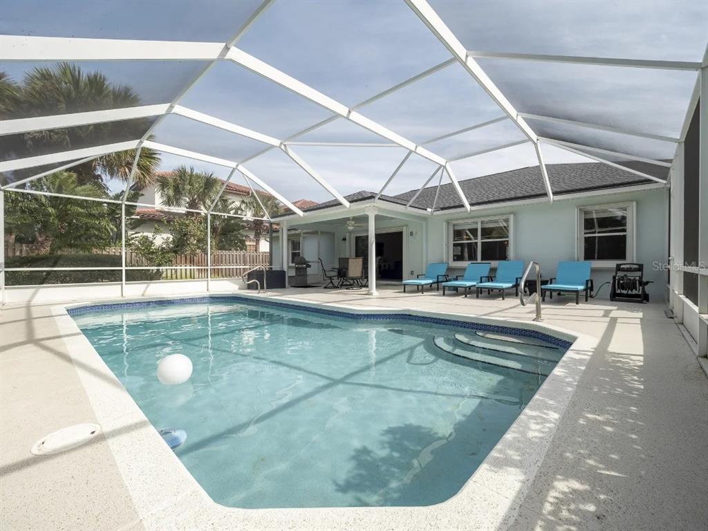 A screened-in patio features a swimming pool and several blue lounge chairs — 19 MAHOE DRIVE N, PALM COAST, FL