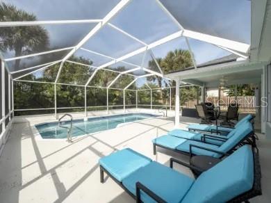 A swimming pool with a screened enclosure sits on a patio next to a house — 19 MAHOE DRIVE N, PALM COAST, FL