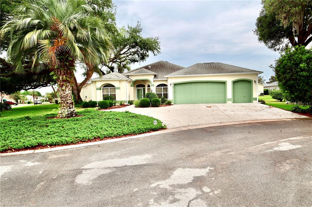A single-story house with a green garage door, a palm tree, and a concrete driveway — 532 CARRERA DRIVE, LADY LAKE, FL