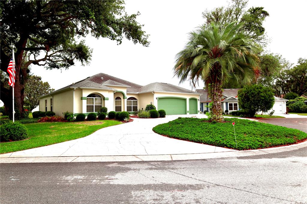 A single-story house with a green garage door, a palm tree, and a concrete driveway — 532 CARRERA DRIVE, LADY LAKE, FL