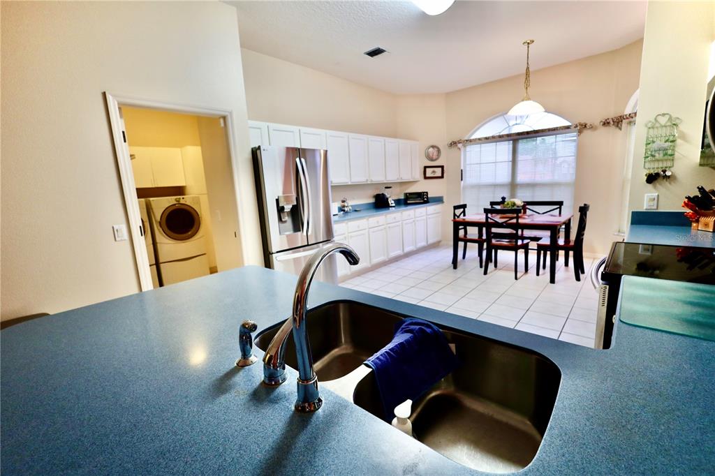 A kitchen with white cabinets, blue countertops, stainless steel appliances, and an adjacent dining area — 532 CARRERA DRIVE, LADY LAKE, FL