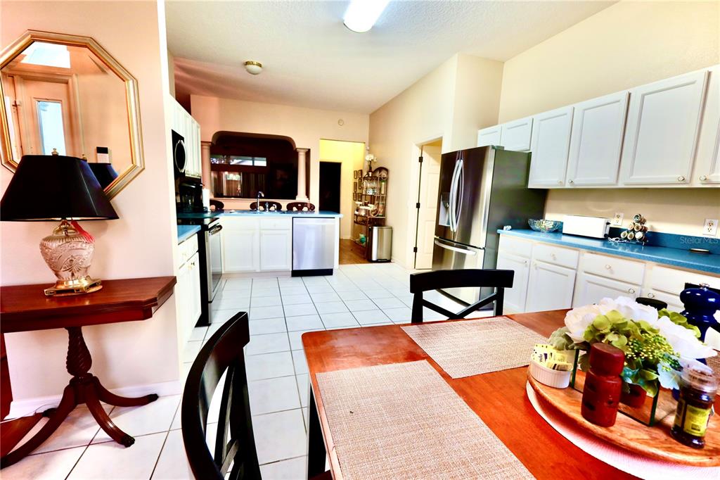 A kitchen and dining area with white cabinets, blue countertops, and tile flooring — 532 CARRERA DRIVE, LADY LAKE, FL