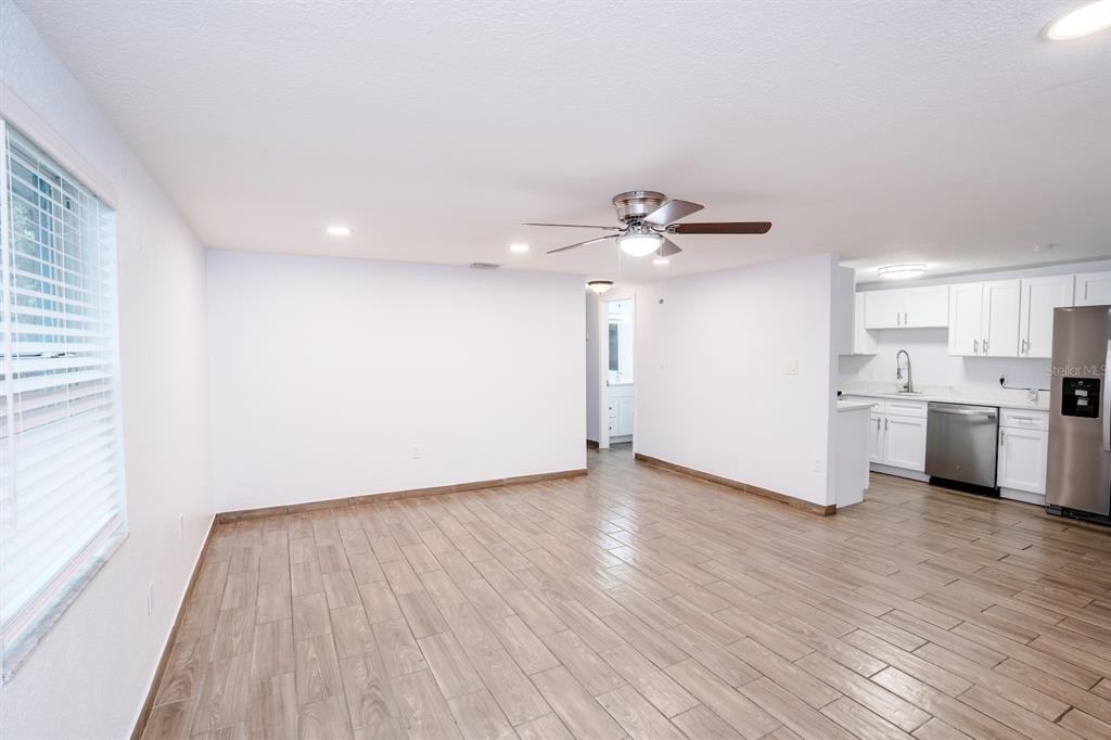 An open-concept living area features wood-look tile flooring, a ceiling fan, and a white kitchen — 503 MOORE AVENUE, SEFFNER, FL