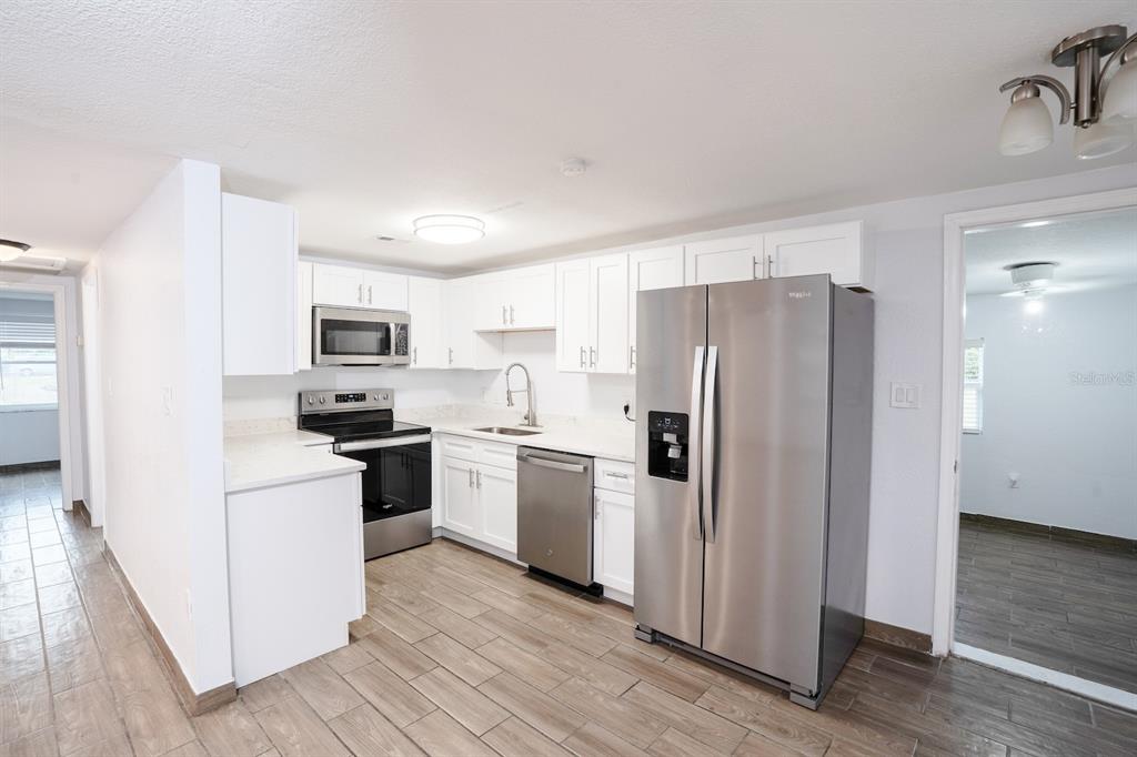 A kitchen with white cabinets, stainless steel appliances, and wood-look tile flooring — 503 MOORE AVENUE, SEFFNER, FL