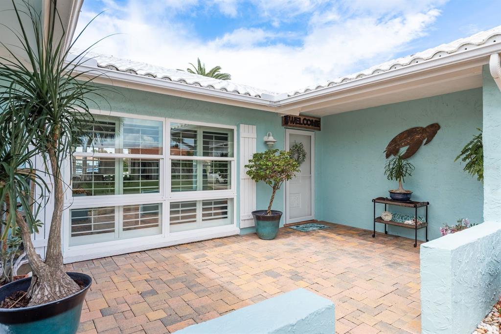 A light blue house exterior features a brick-paved patio, large windows, and a front door — 3301 SEAWAY DRIVE, NEW PORT RICHEY, FL