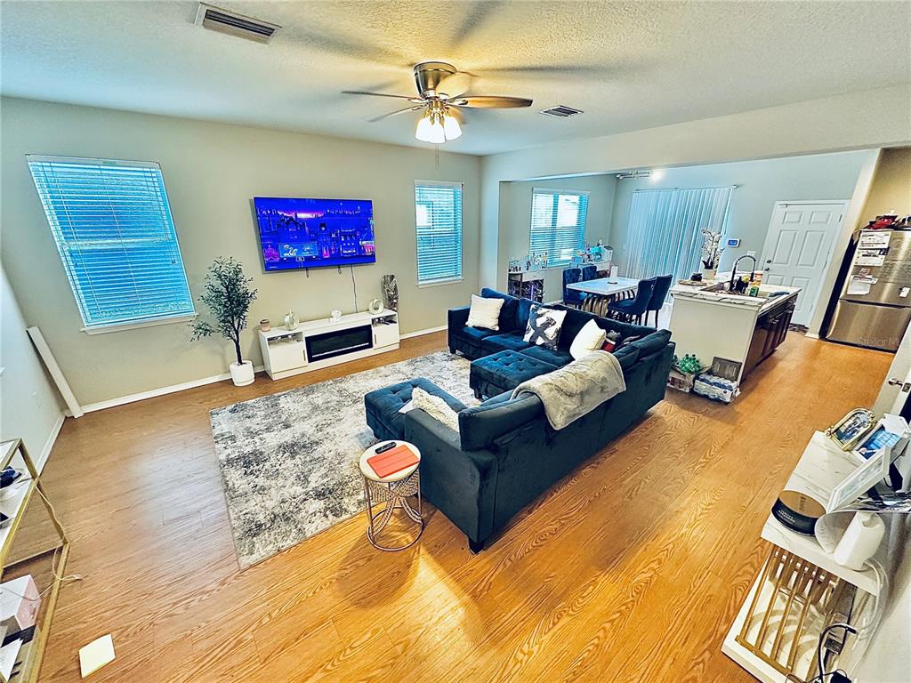 A living room with a dark blue sectional sofa, a television, and wood-look flooring — 4411 BANYAN TREE PLACE, RIVERVIEW, FL