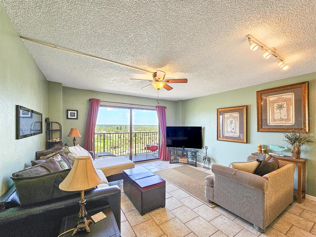 A living room features tile floors, a ceiling fan, and a balcony with outdoor views — 3600 S OCEAN SHORE BOULEVARD UNIT 720, FLAGLER BEACH, FL