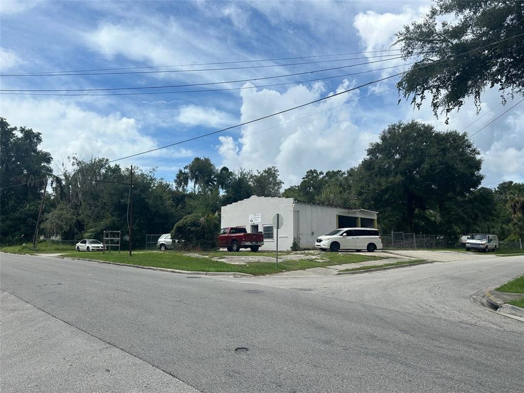A white commercial building sits on a corner lot with several parked vehicles — 800 S ADELLE AVENUE, DELAND, FL