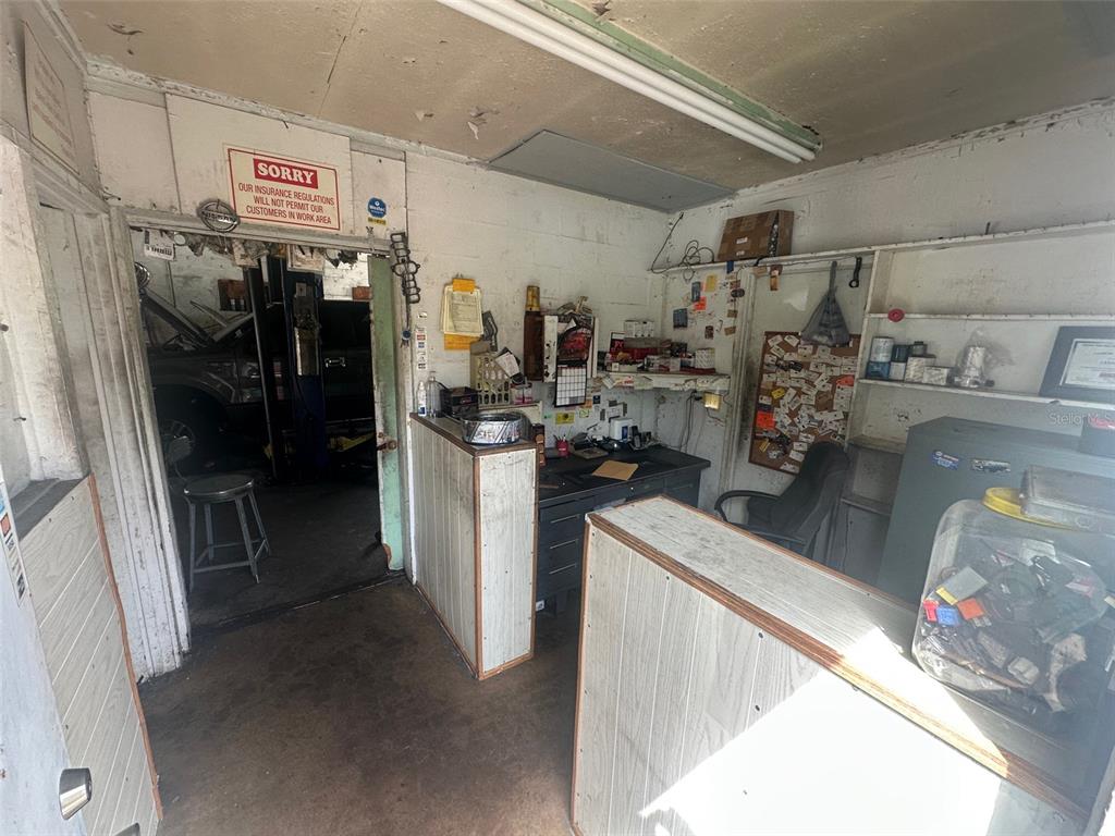 A cluttered auto repair shop office features a service counter, desk, and doorway to a garage — 800 S ADELLE AVENUE, DELAND, FL