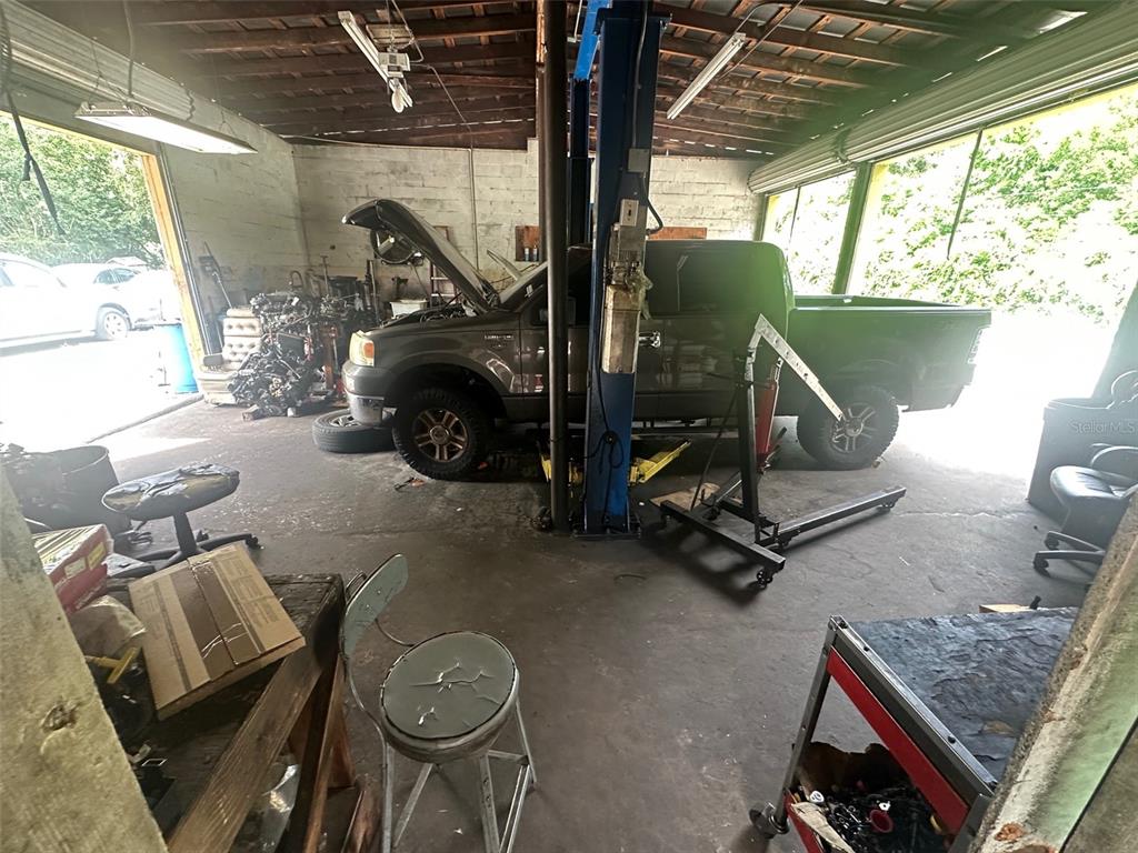 A garage workspace features a dark pickup truck raised on a hydraulic lift — 800 S ADELLE AVENUE, DELAND, FL