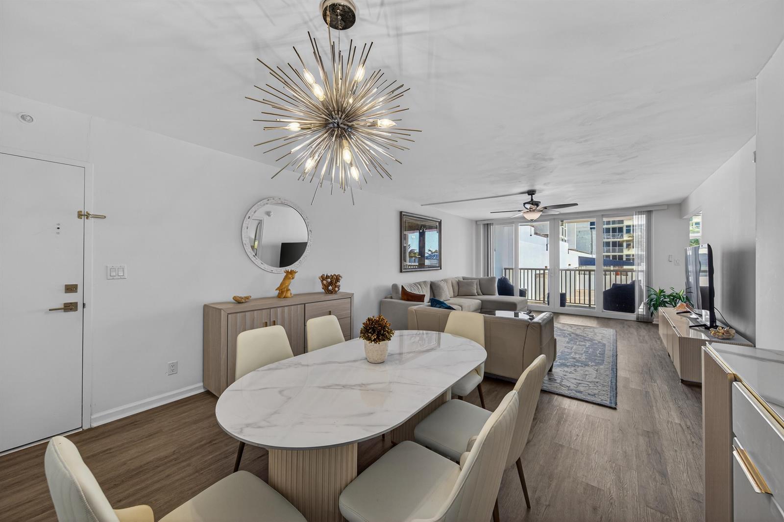 A dining area with a marble table and starburst chandelier opens into a living room — 1370 S Ocean Boulevard # 306, Pompano Beach FL 33062, POMPANO BEACH, FL