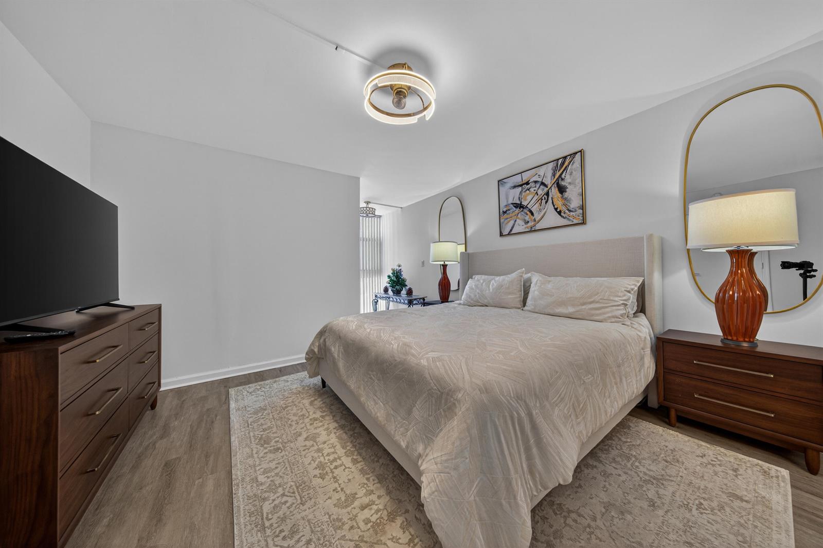 A bedroom features a bed with a light-colored headboard, two wooden dressers, and wall mirrors — 1370 S Ocean Boulevard # 306, Pompano Beach FL 33062, POMPANO BEACH, FL