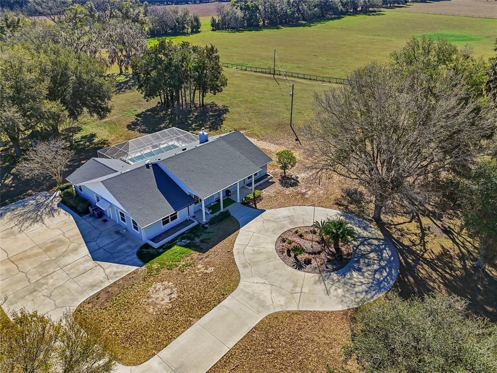 A covered porch features white columns, a hanging bench, and a patch of artificial turf — 9115 NW 170TH STREET, ALACHUA, FL
