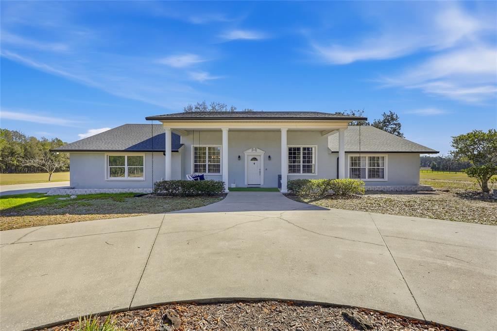 A covered patio features a wooden picnic table, ceiling fans, and a screened-in swimming pool — 9115 NW 170TH STREET, ALACHUA, FL