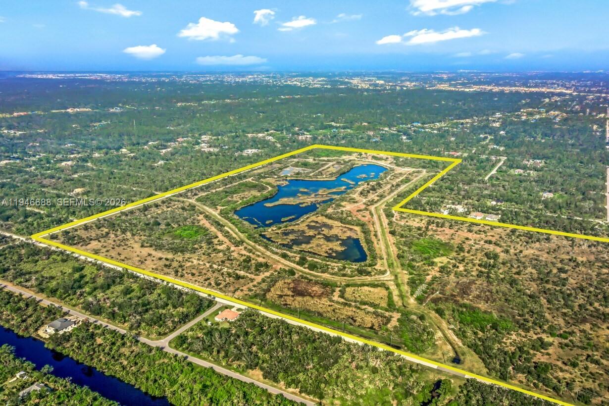 An aerial view shows a large, undeveloped plot of land containing a central lake — PORT CHARLOTTE, FL