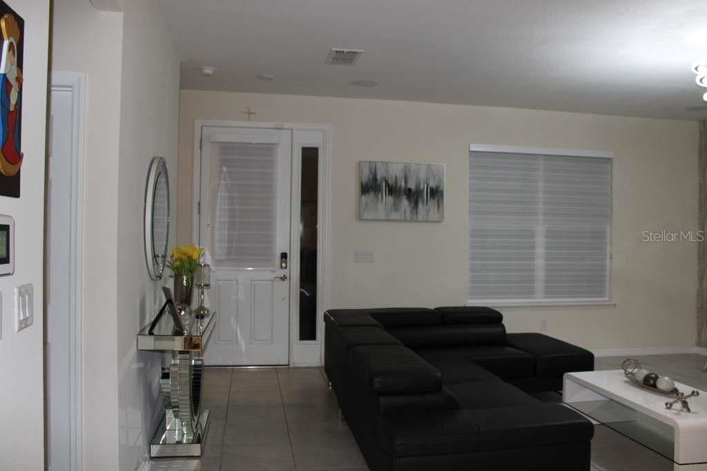 A living room features a black sectional sofa, a white coffee table, and a front door — 1723 FLOURISH AVENUE, KISSIMMEE, FL
