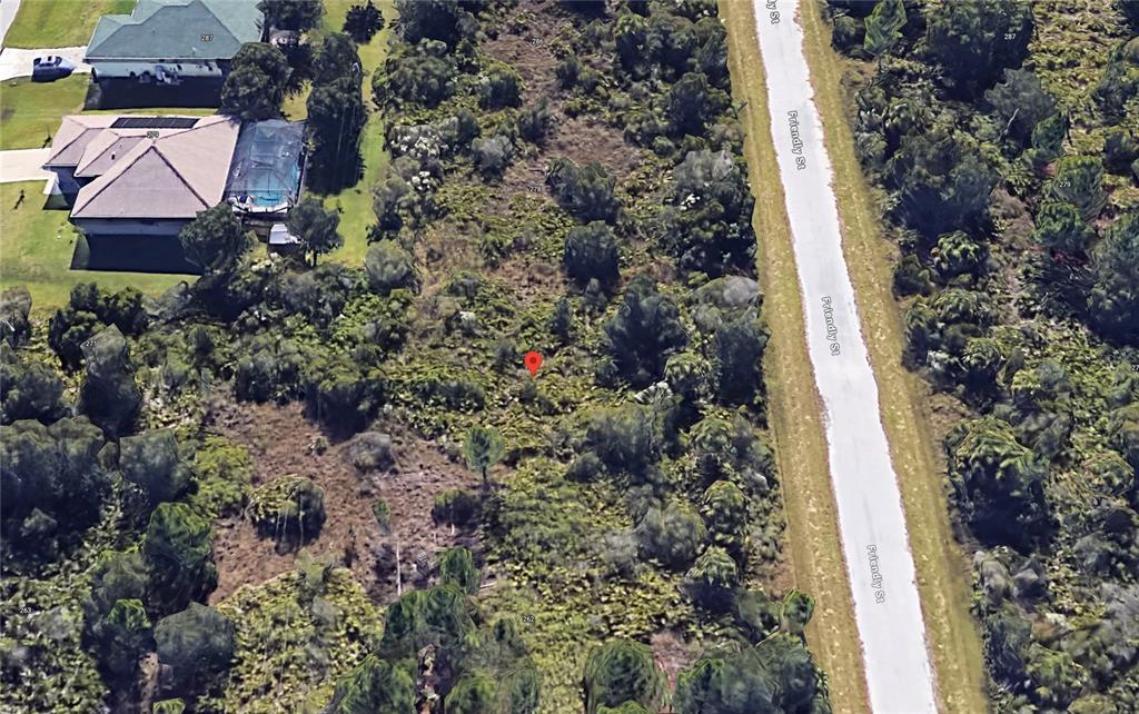 This aerial view shows a vacant, wooded residential lot next to a paved road — 270 FRIENDLY STREET, PORT CHARLOTTE, FL